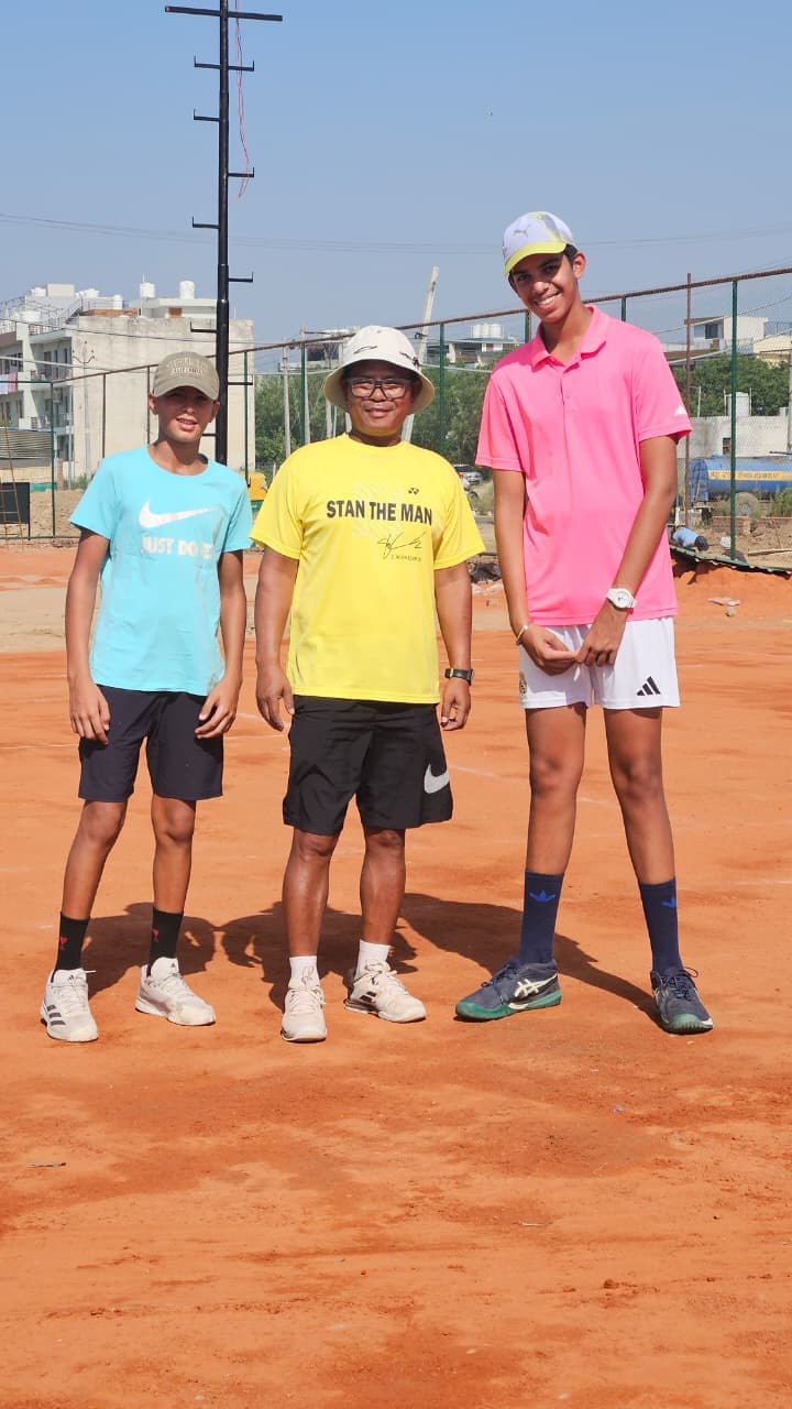 Coach with two junior students on the clay court