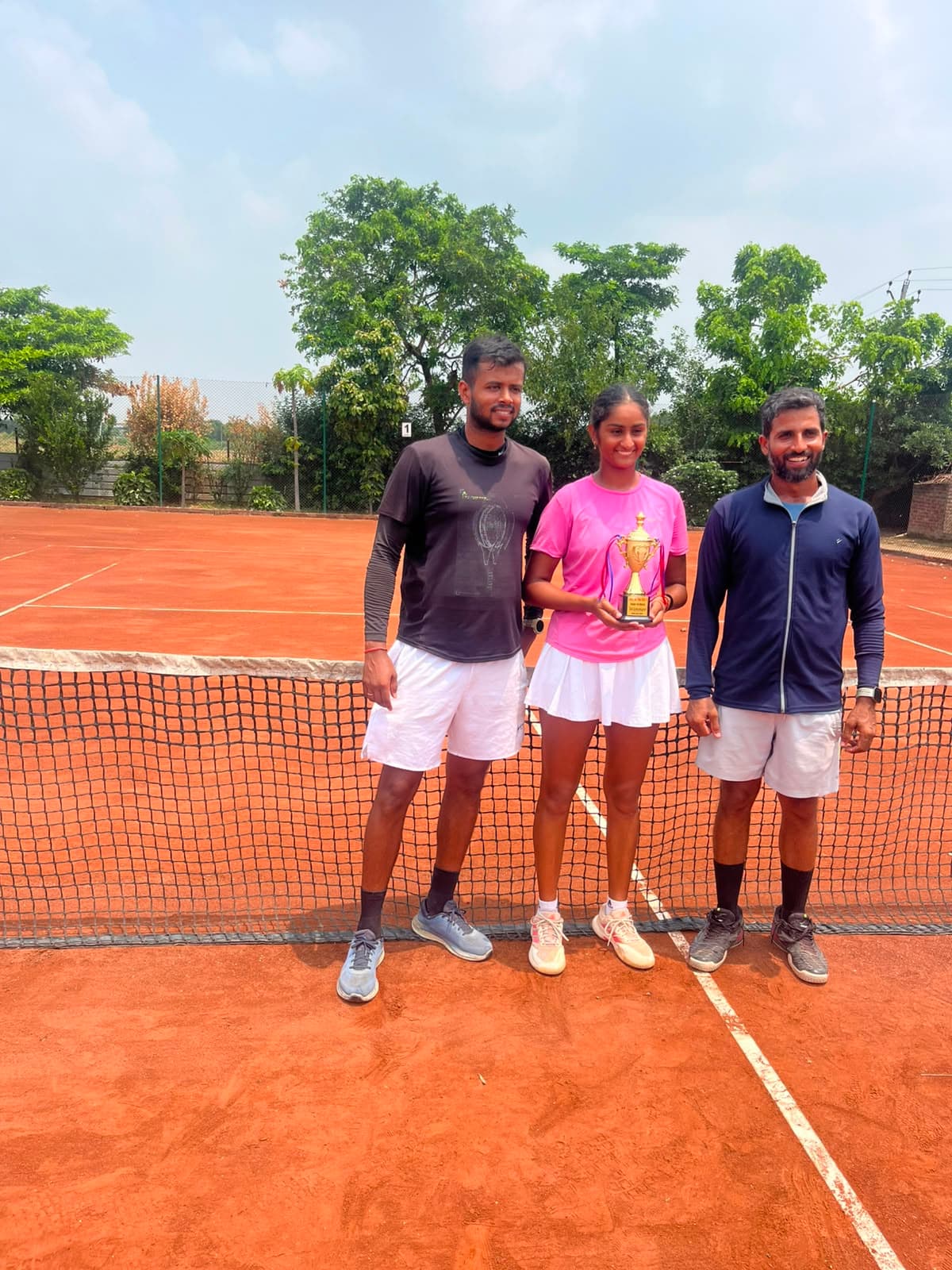 Coach and player celebrating with trophy at the net